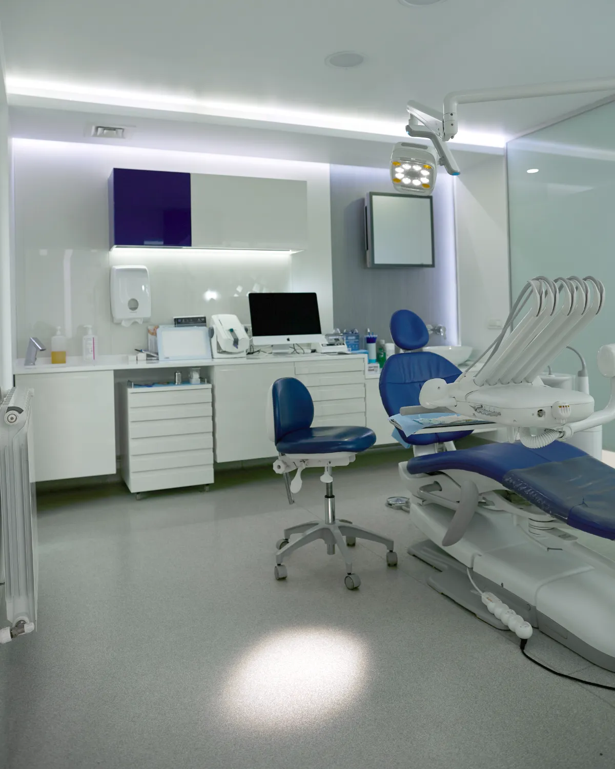 A second treatment room at our partner clinic in Bucharest, with a blue dental chair, a wall of storage units and a computer at the worktop
